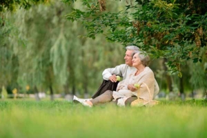 ældre par sidder i græsset og spiser æbler